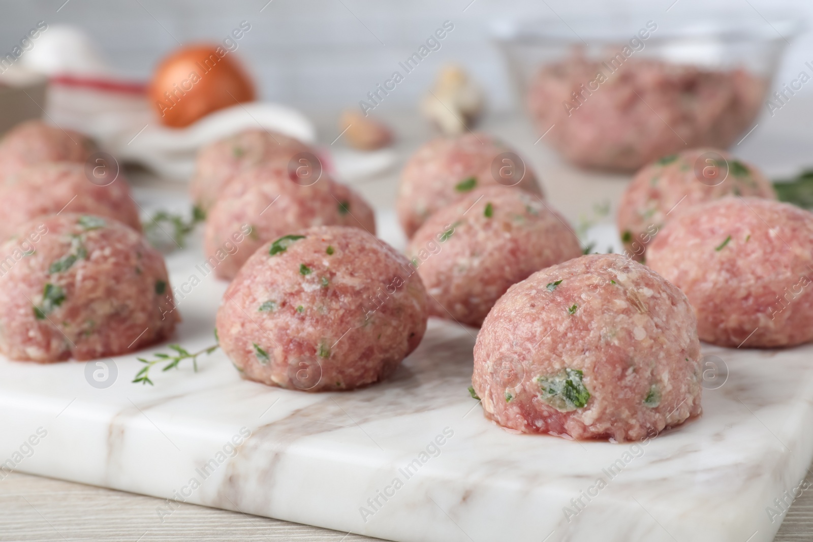 Photo of Many fresh raw meatballs on white marble board, closeup