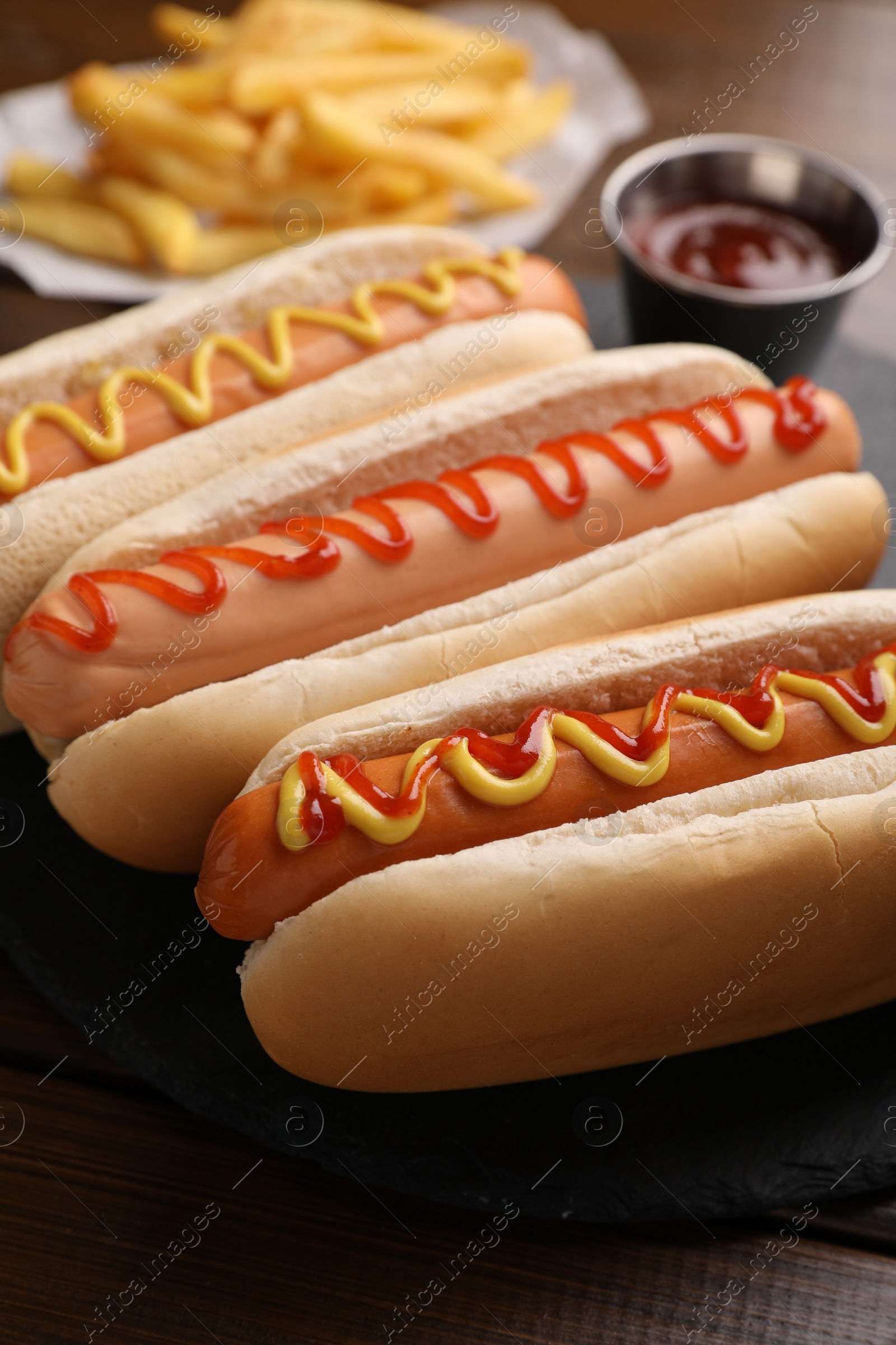 Photo of Delicious hot dogs with sauces on wooden table, closeup