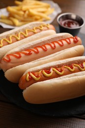 Delicious hot dogs with sauces on wooden table, closeup