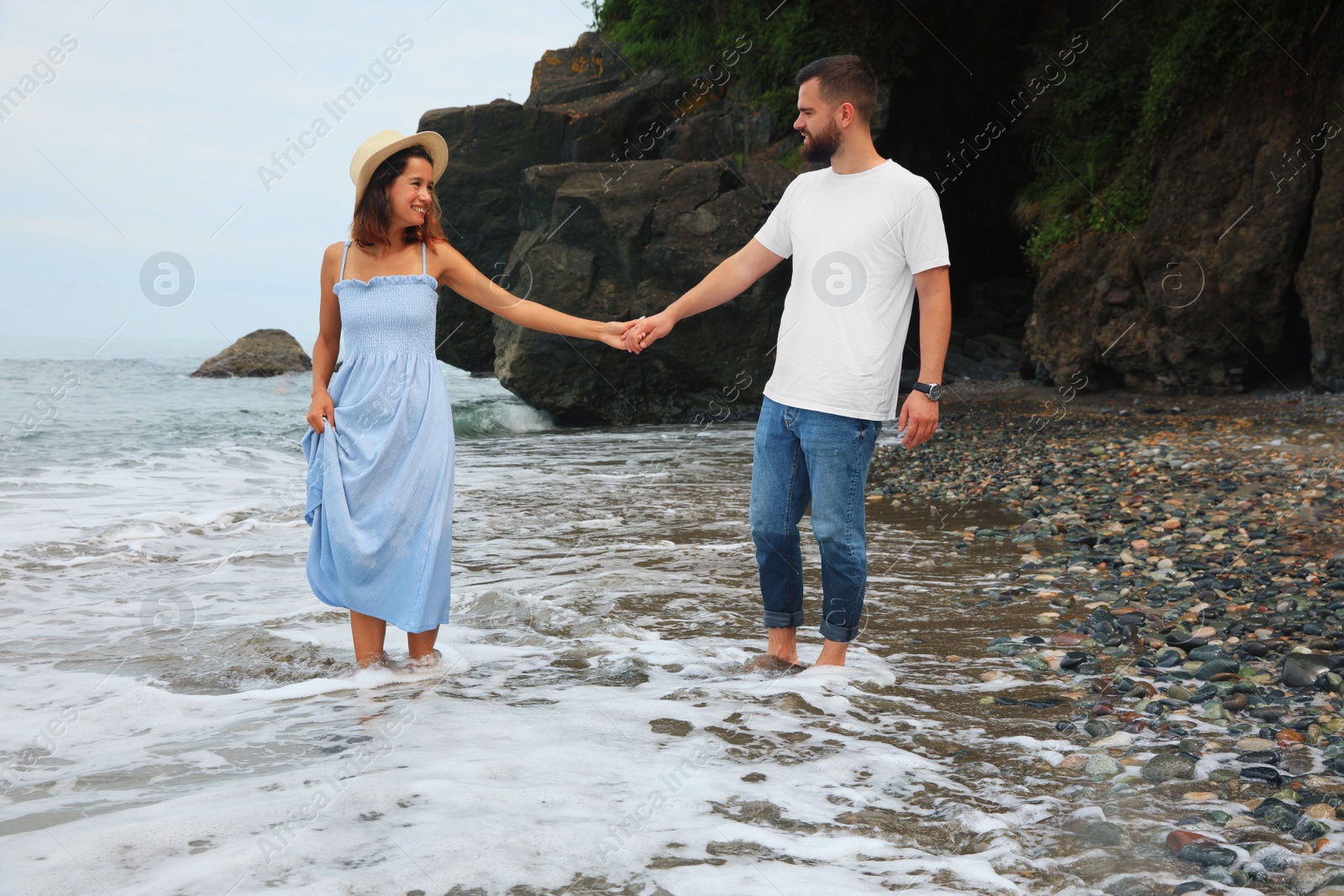 Photo of Happy young couple walking on beach near sea