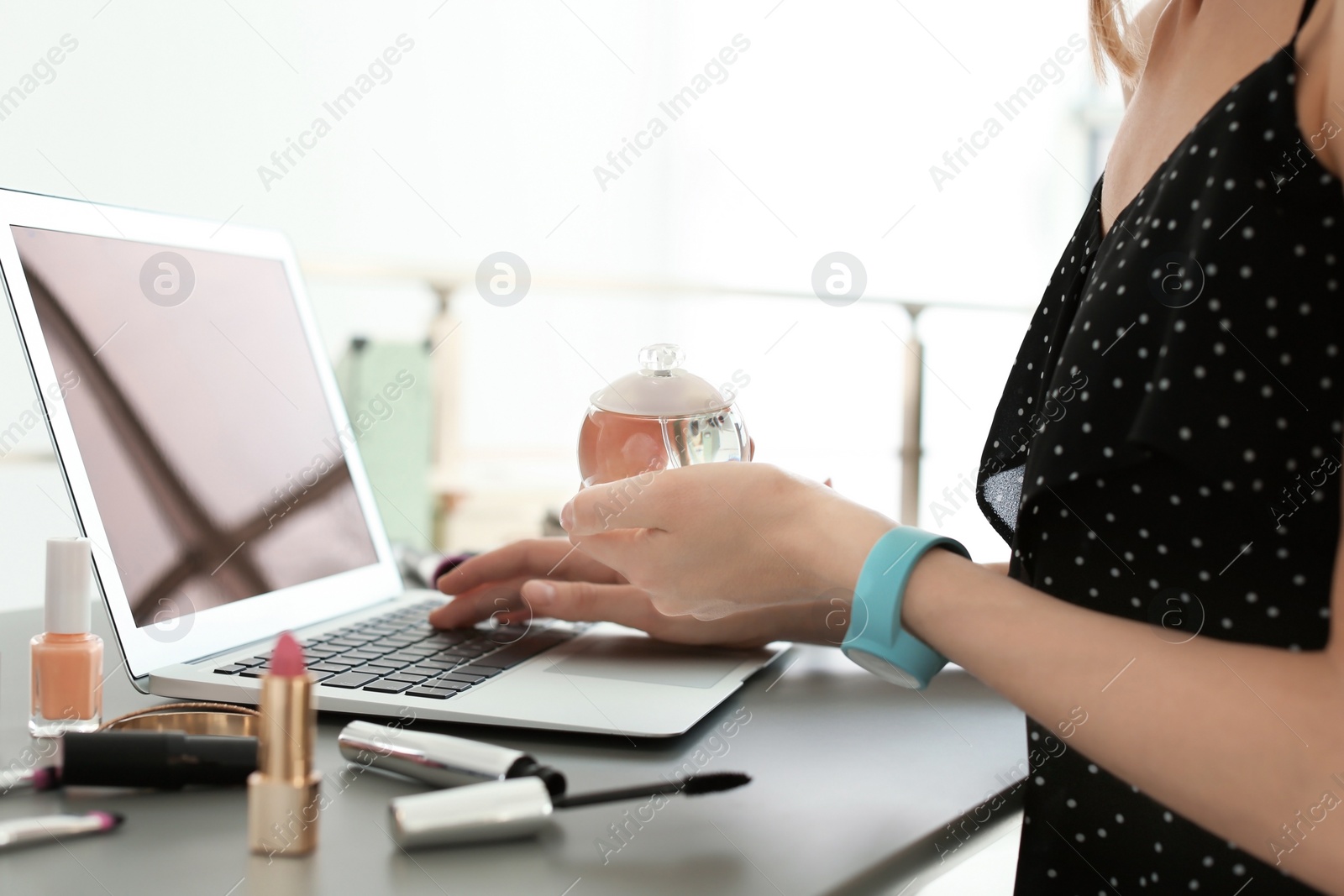 Photo of Young woman with makeup products using laptop at table. Beauty blogger