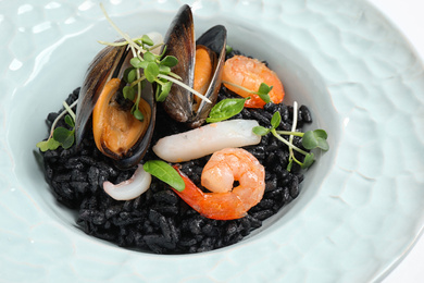 Photo of Delicious black risotto with seafood in plate, closeup