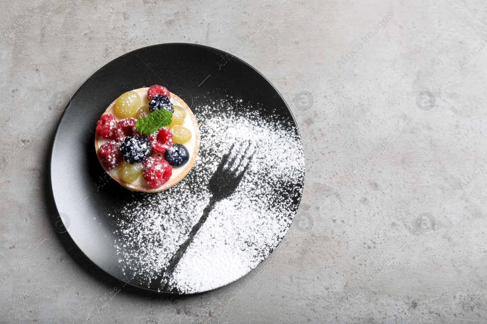 Photo of Delicious tartlet with berries on light grey table, top view
