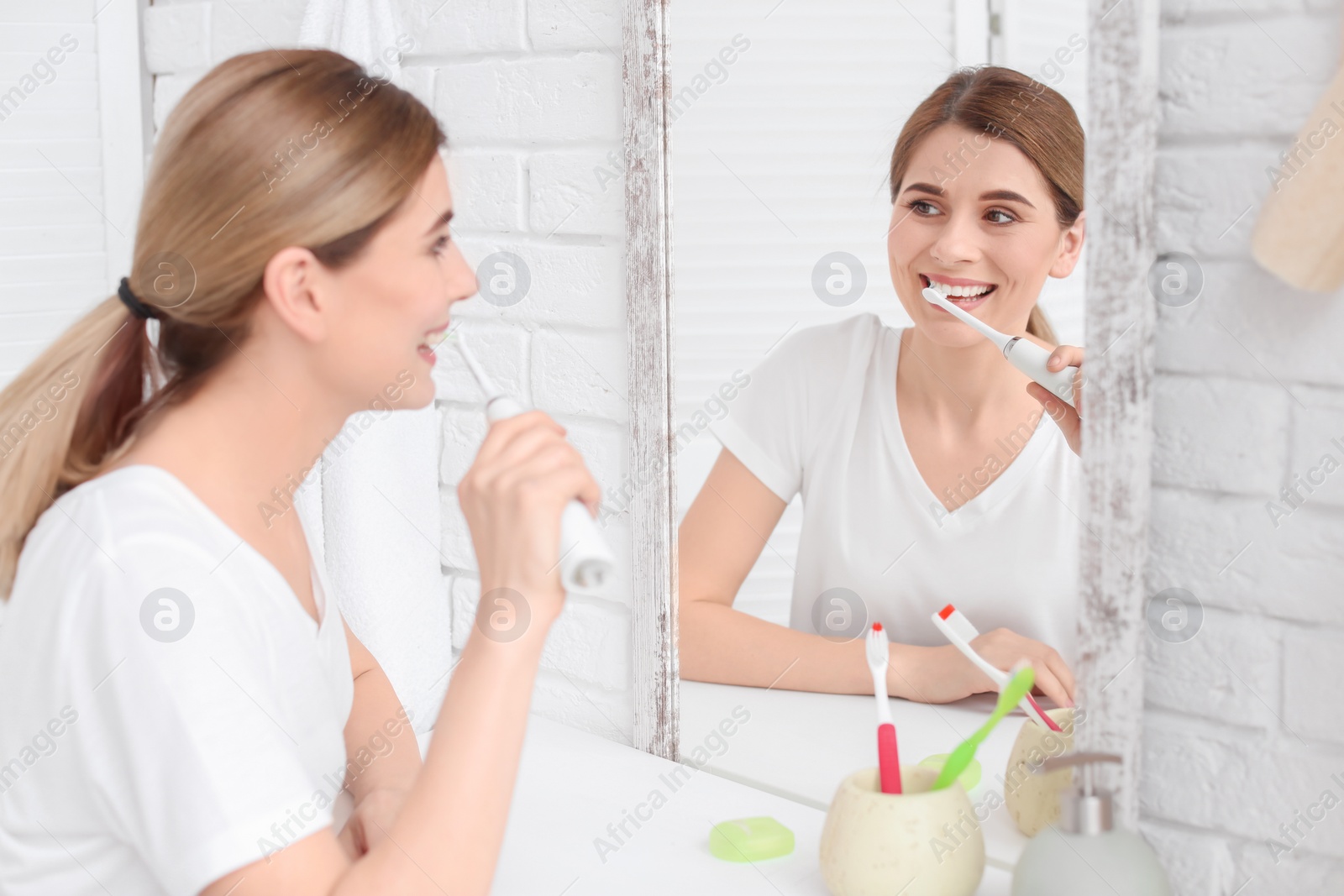 Photo of Young woman brushing her teeth in bathroom