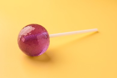 Photo of One tasty lollipop on yellow background, closeup