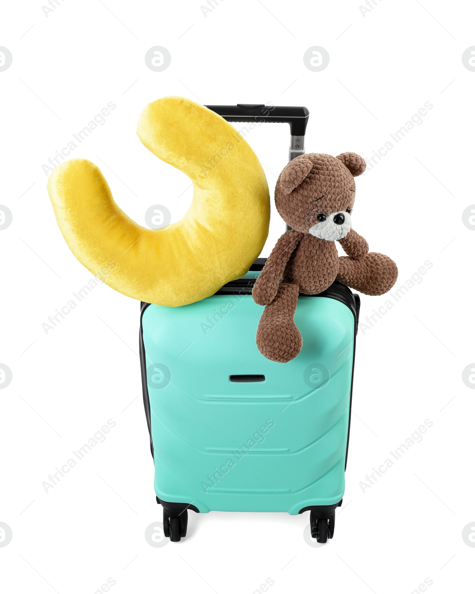 Photo of Soft travel pillow and toy bear on turquoise suitcase isolated on white