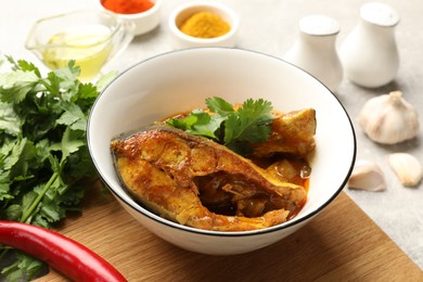 Photo of Tasty fish curry and ingredients on light grey table, closeup. Indian cuisine