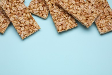 Tasty peanut bars (kozinaki) on light blue background, flat lay. Space for text