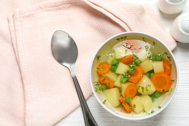 Photo of Bowl of fresh homemade vegetable soup served on white wooden table, flat lay