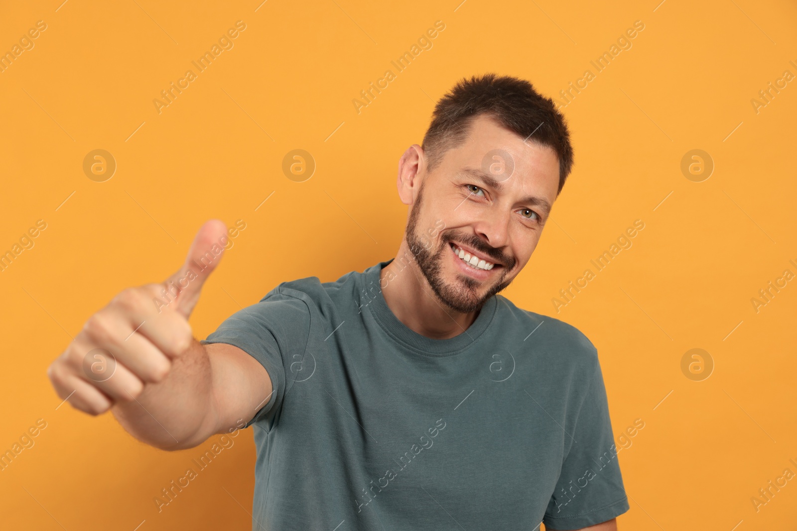 Photo of Man showing thumb up on orange background