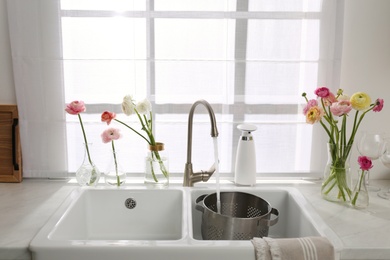 Photo of Light kitchen decorated with beautiful fresh ranunculus flowers