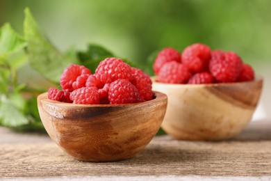 Tasty ripe raspberries in bowl on wooden table outdoors. Space for text