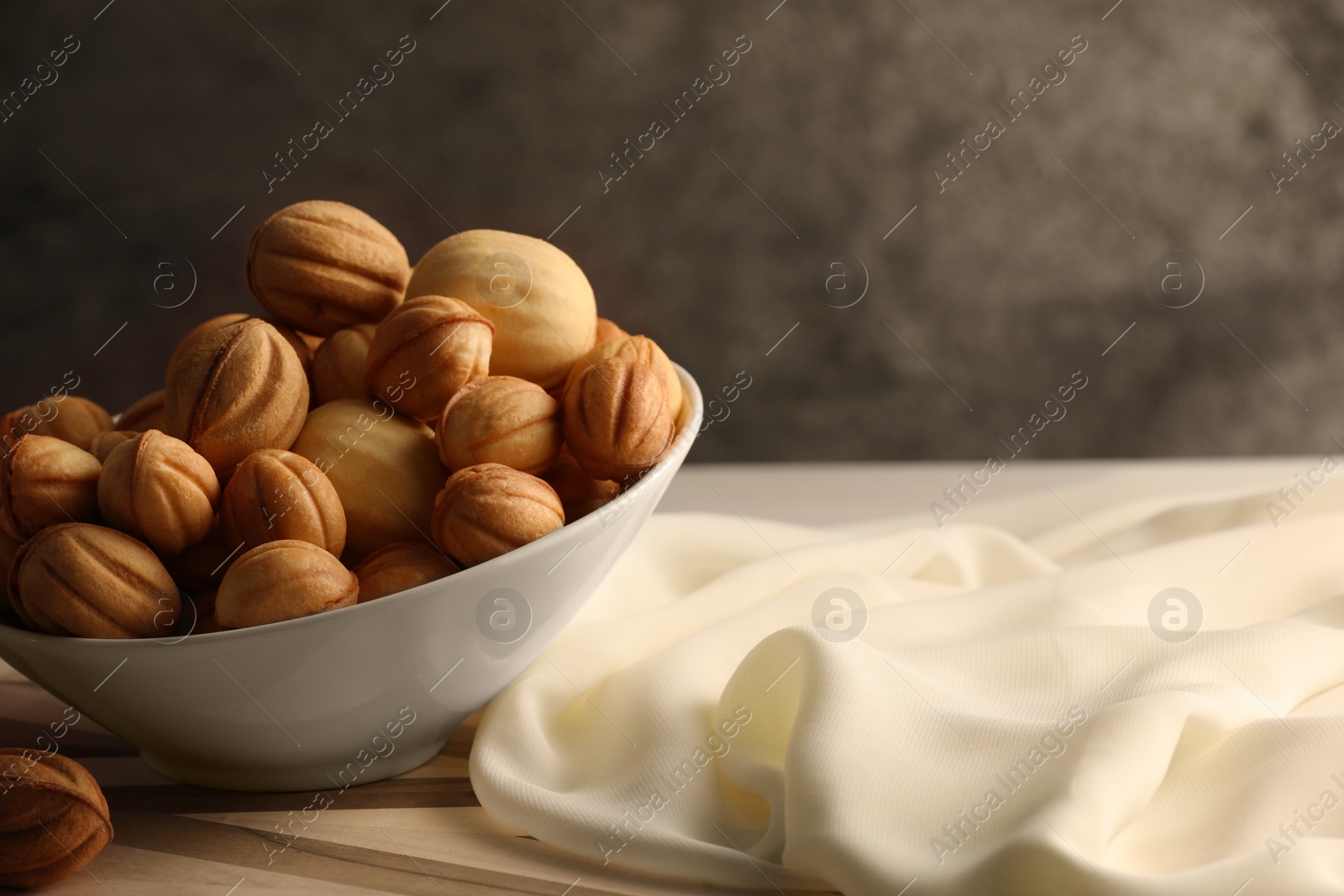 Photo of Freshly baked walnut shaped cookies on wooden board, space for text. Homemade pastry filled with caramelized condensed milk