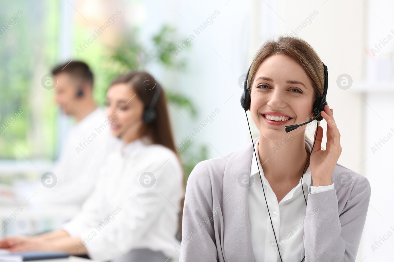 Photo of Young female receptionist with headset in office