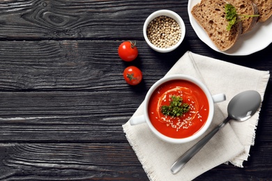 Photo of Fresh homemade tomato soup served with bread on wooden table, top view. Space for text