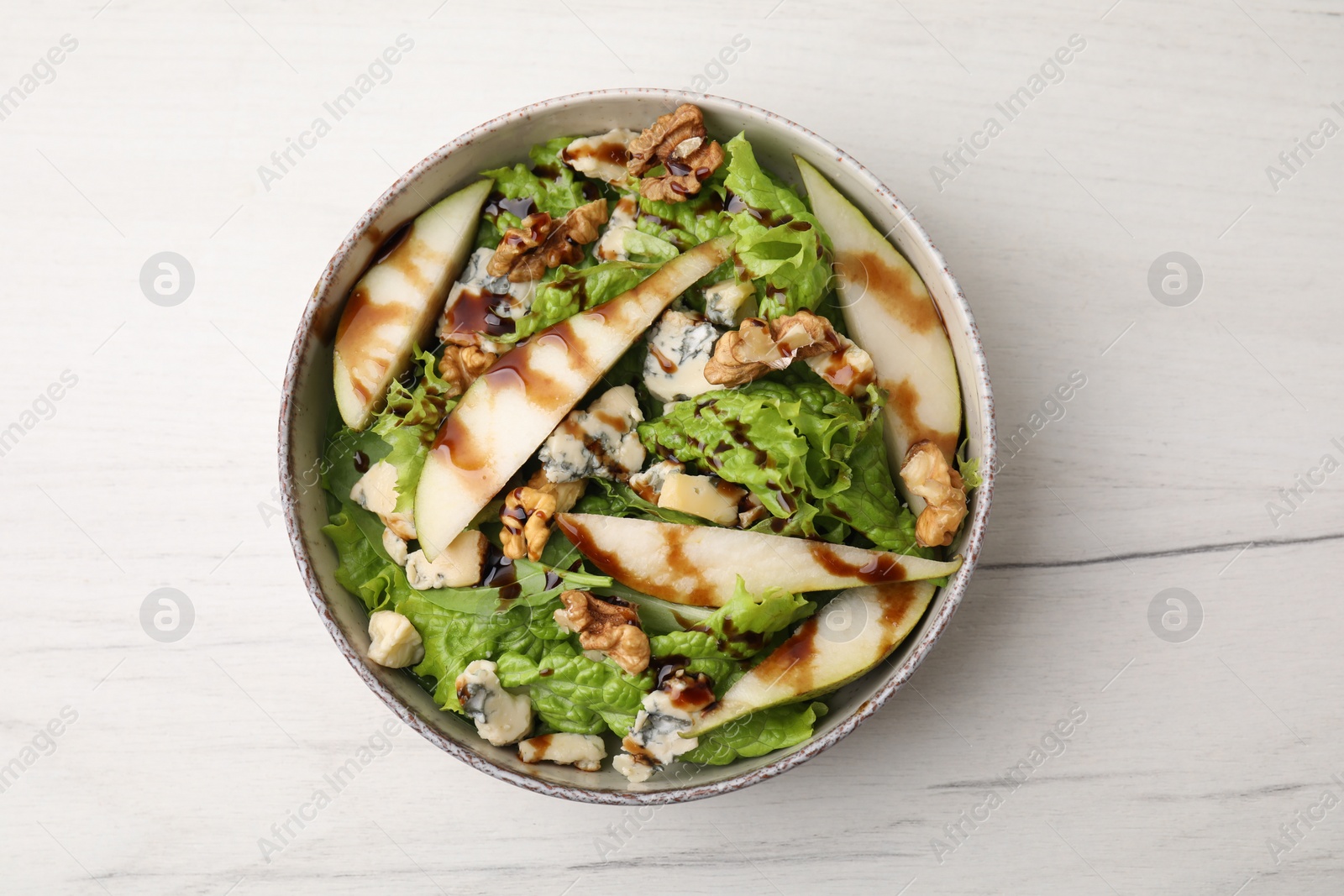 Photo of Delicious pear salad with sauce in bowl on light table, top view