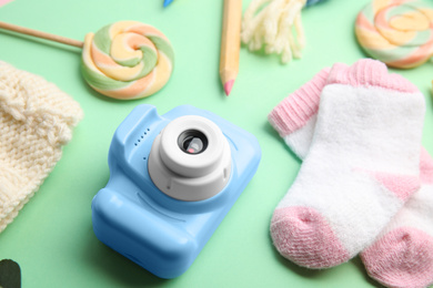 Photo of Light blue toy camera and little socks on light green background. Future photographer