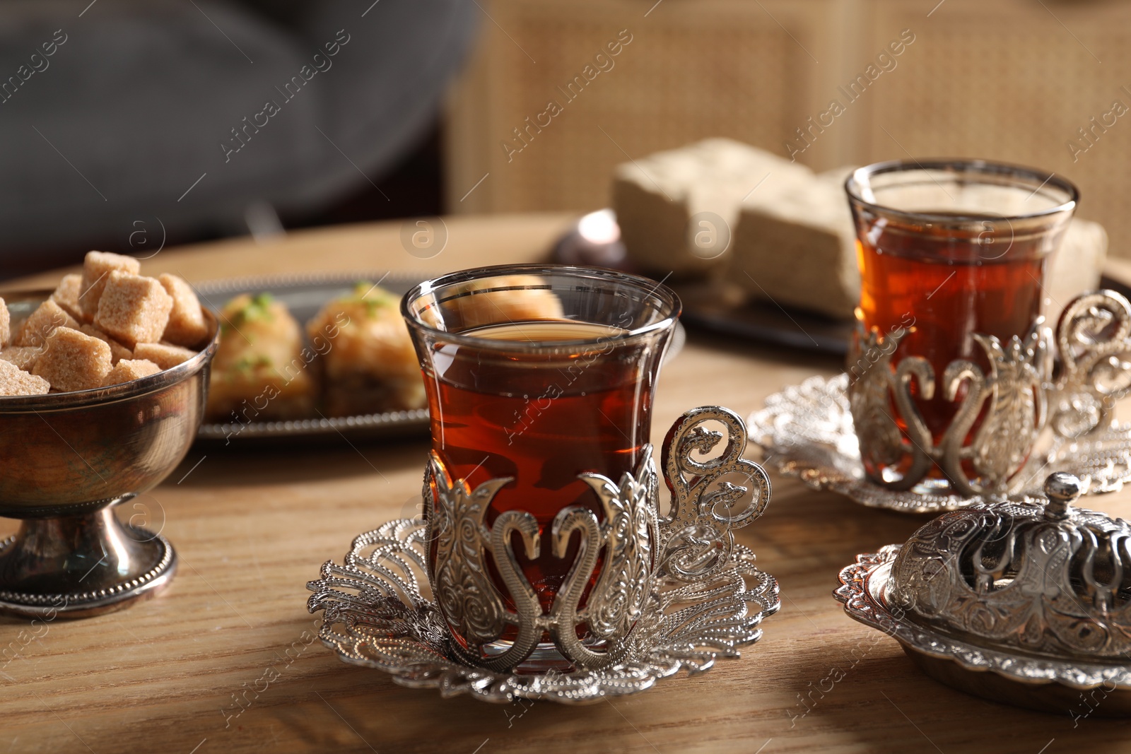 Photo of Traditional Turkish tea and sweets served in vintage tea set on wooden table