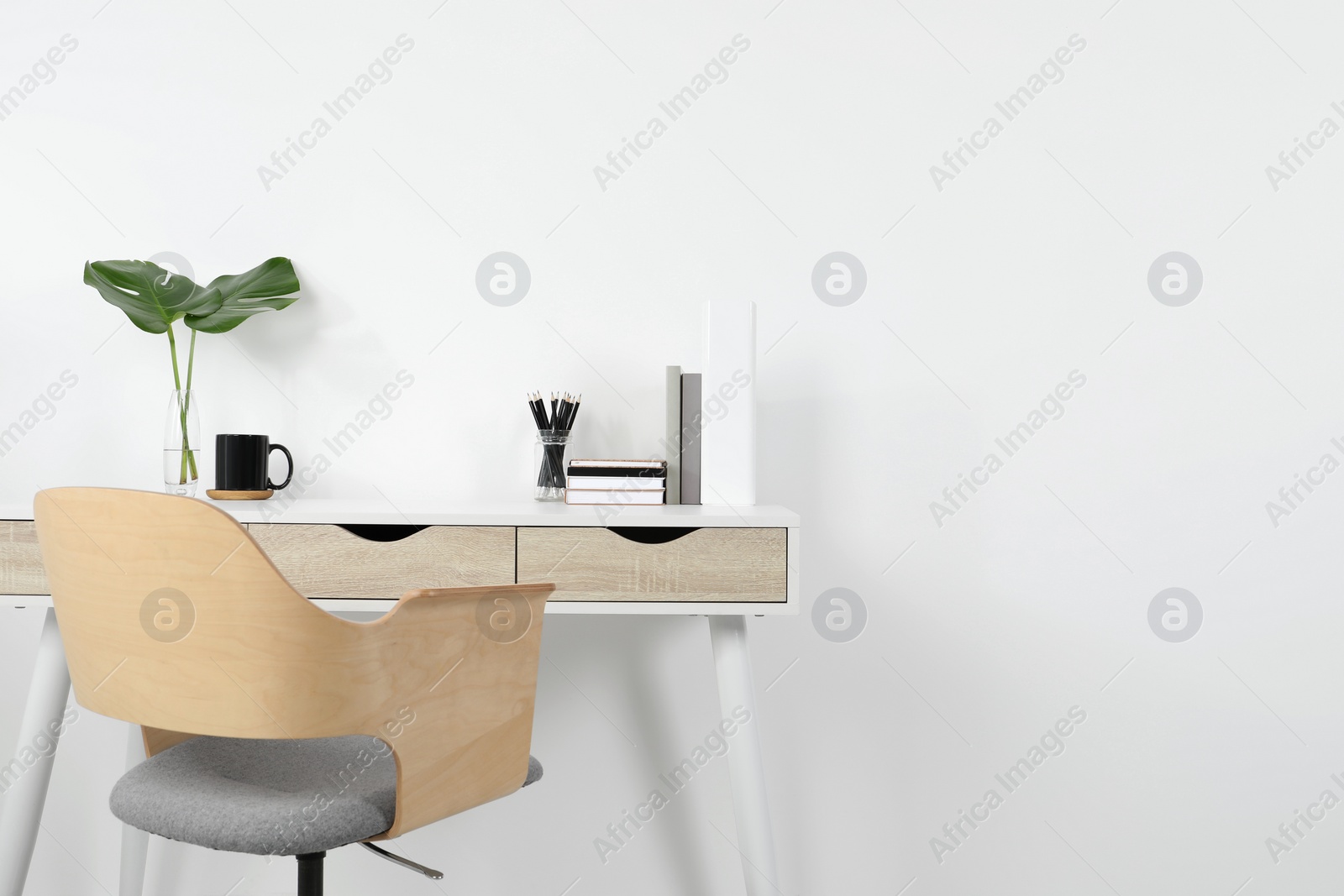 Photo of Comfortable workplace with white desk near wall. Space for text