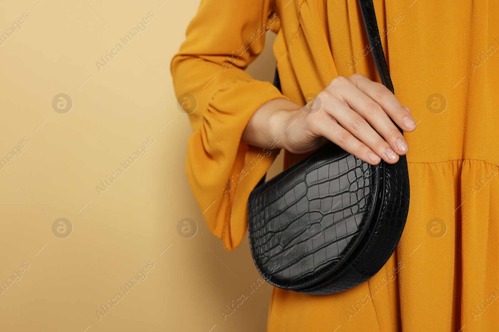 Photo of Woman with stylish bag on beige background, closeup. Space for text