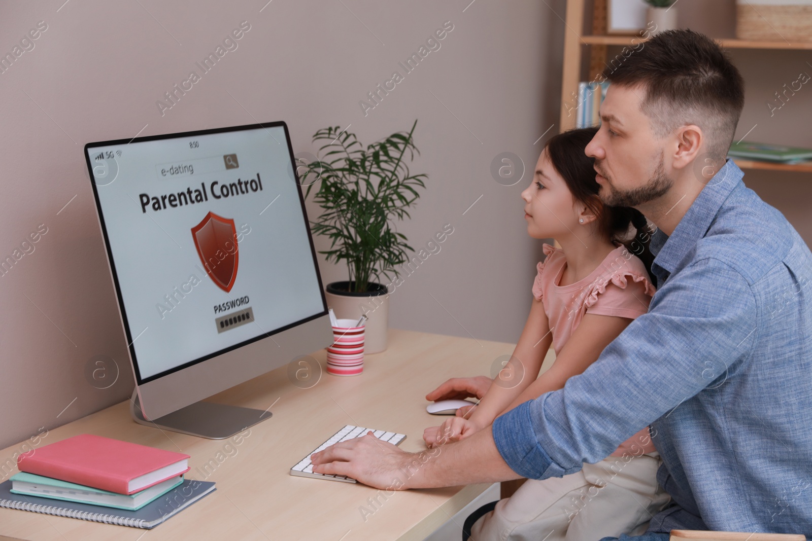 Photo of Dad installing parental control on computer at table indoors. Child safety