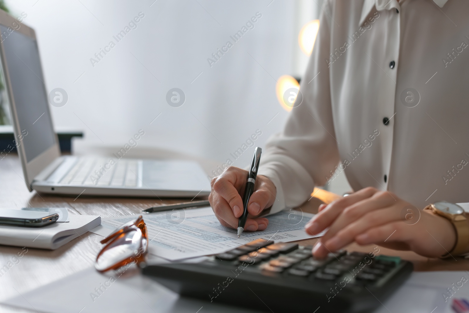 Photo of Tax accountant with calculator working at table in office, closeup