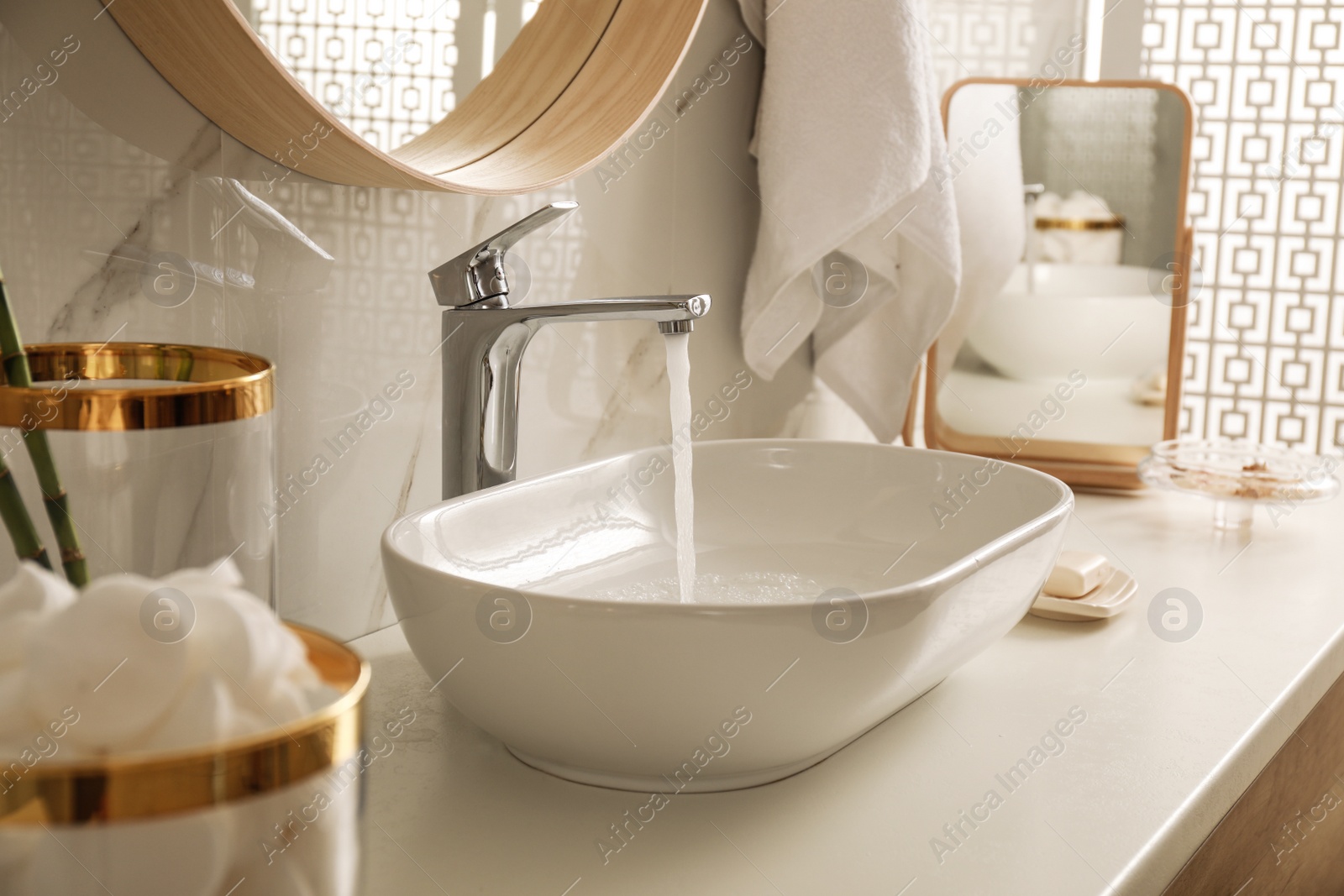 Photo of Sink with running water in stylish bathroom interior