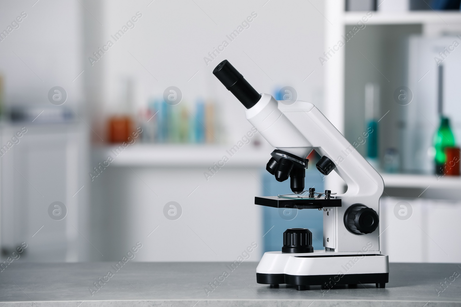 Photo of Modern medical microscope on grey table in laboratory, space for text