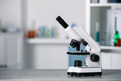 Modern medical microscope on grey table in laboratory, space for text