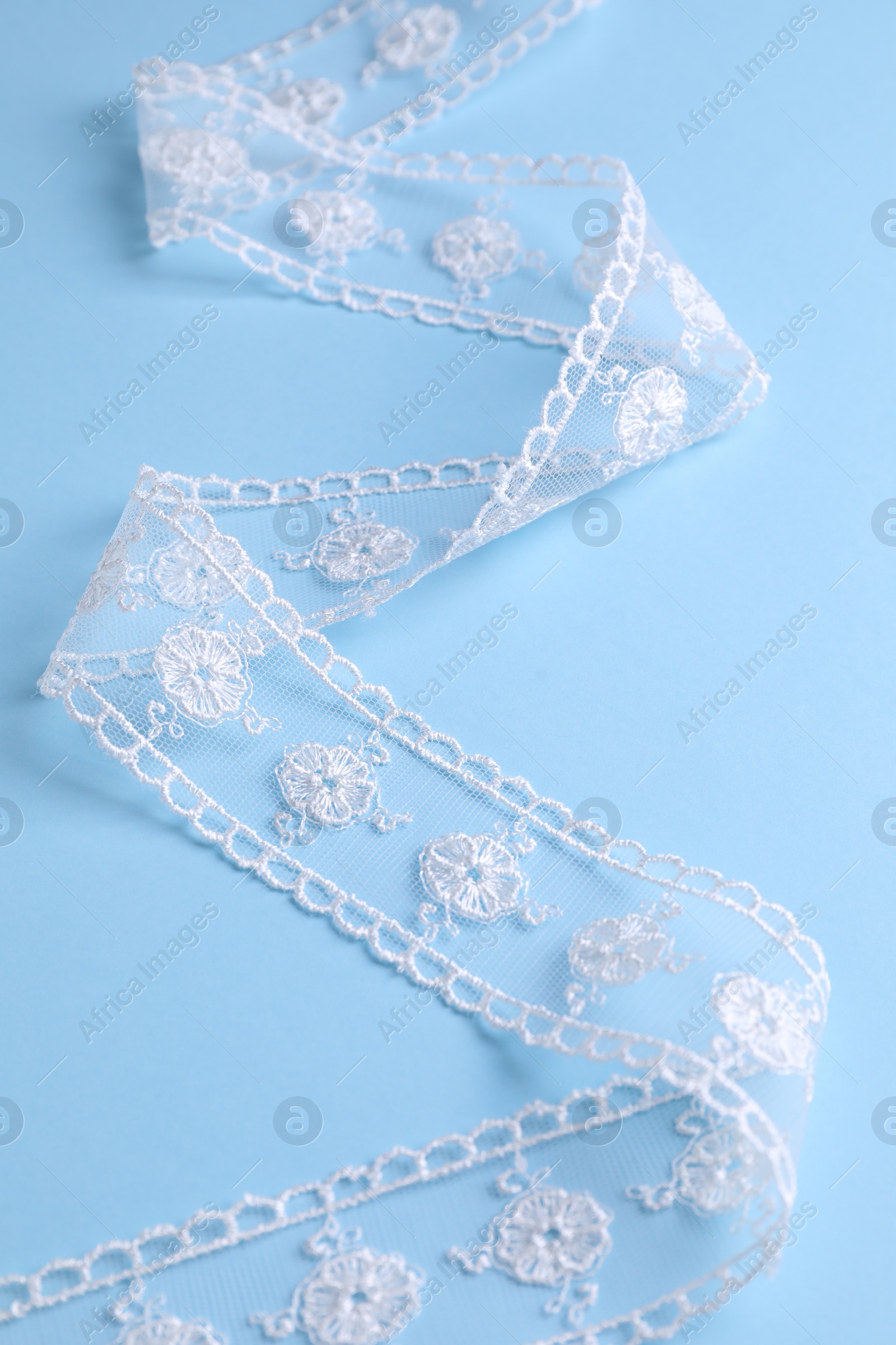 Photo of White lace on light blue background, closeup view