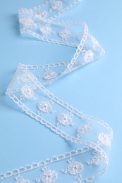 Photo of White lace on light blue background, closeup view