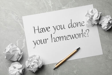 Image of Paper sheet with phrase HAVE YOU DONE YOUR HOMEWORK? on grey marble table, flat lay 