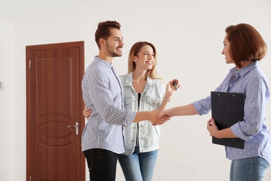 Photo of Real estate agent with young couple in new apartment