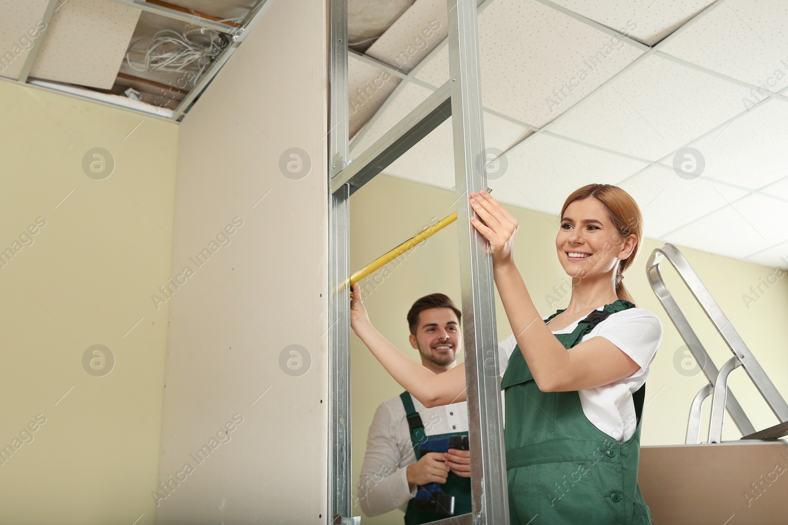 Photo of Workers installing drywall indoors. Home repair service