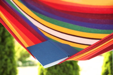 Photo of Colorful hammock with book outdoors on sunny day