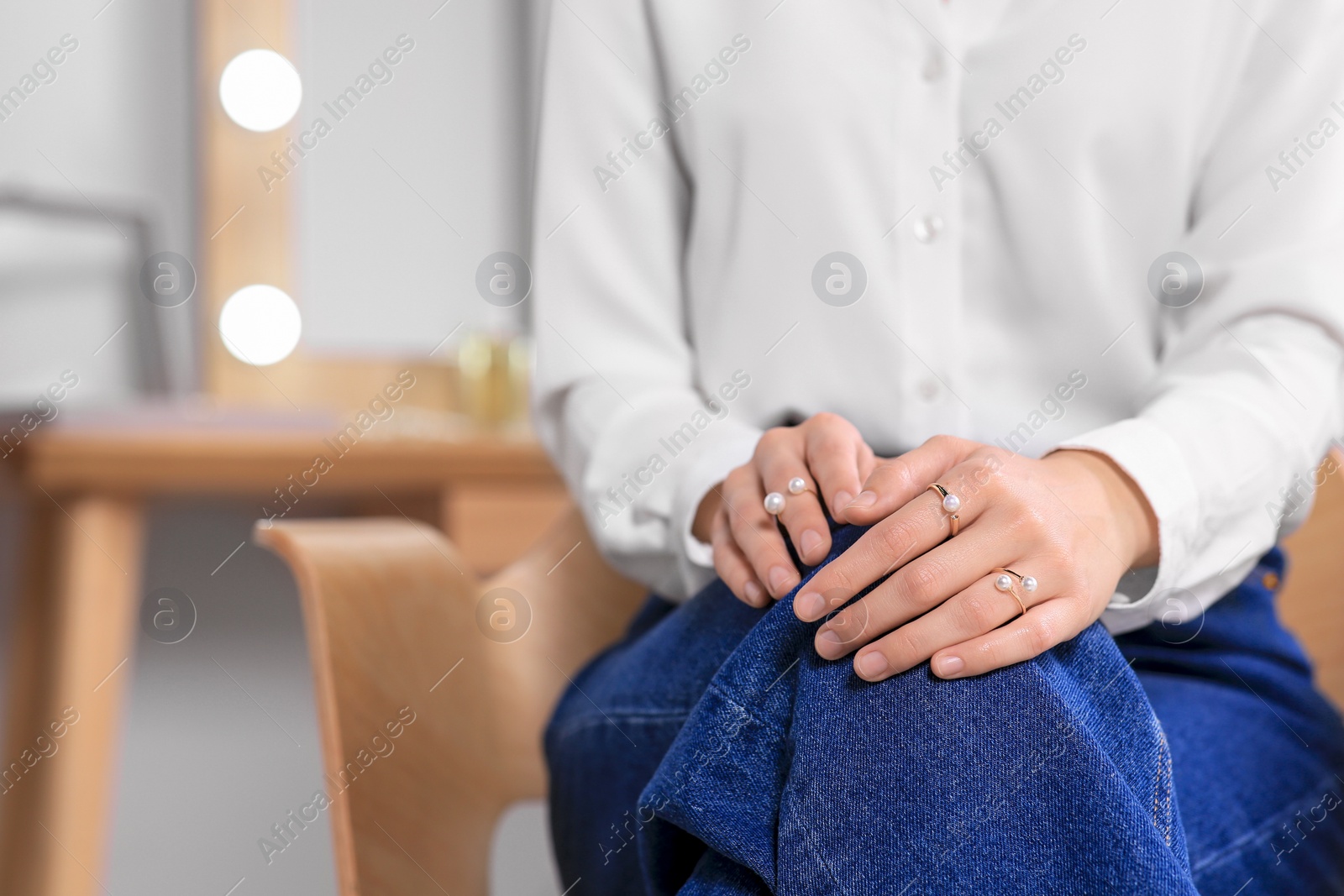 Photo of Young woman wearing elegant rings with pearls indoors, closeup. Space for text