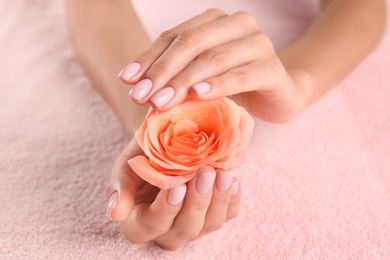 Photo of Closeup view of beautiful female hands with rose on towel. Spa treatment