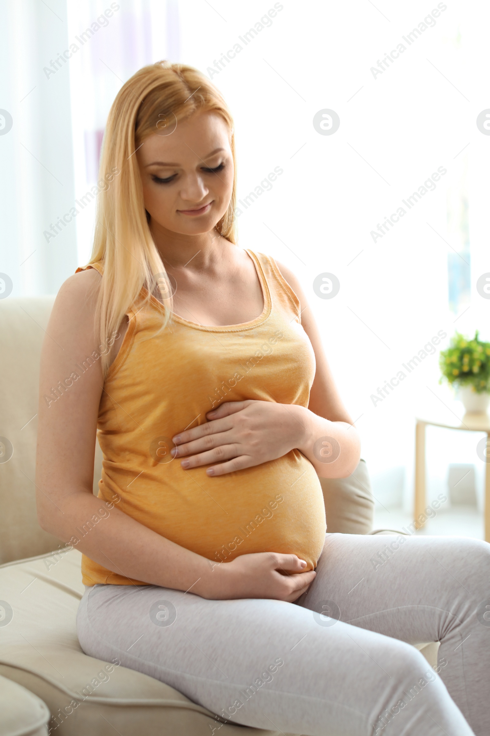 Photo of Beautiful pregnant woman sitting in light room at home