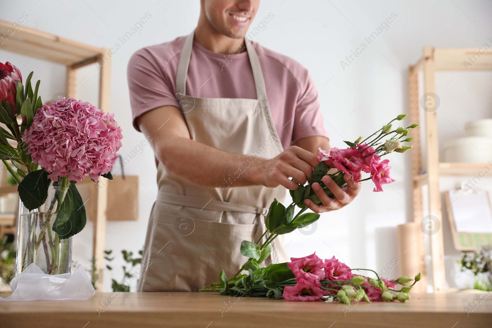 Photo of Florist making beautiful bouquet at table in workshop, closeup