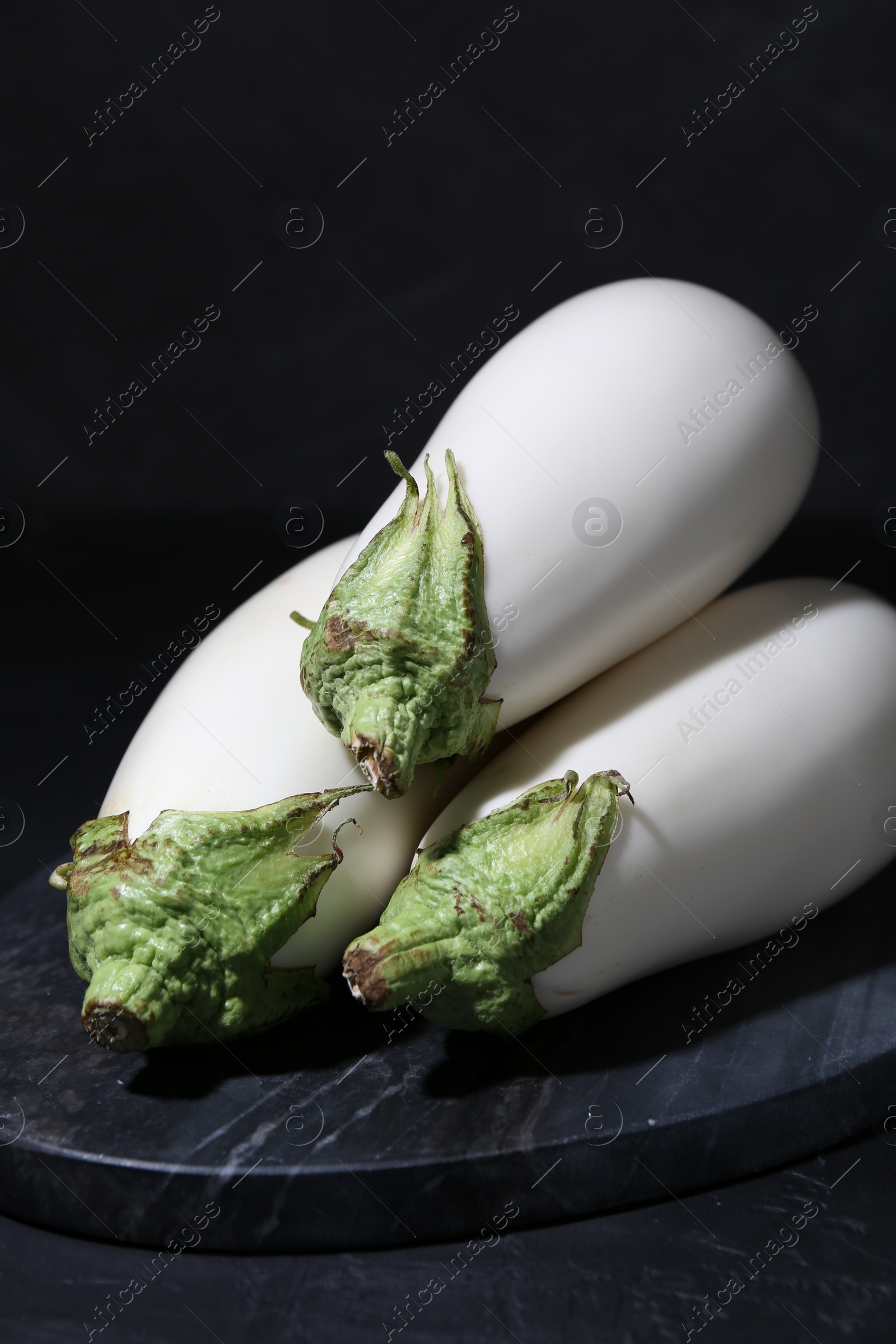 Photo of Fresh white eggplants on black table, closeup