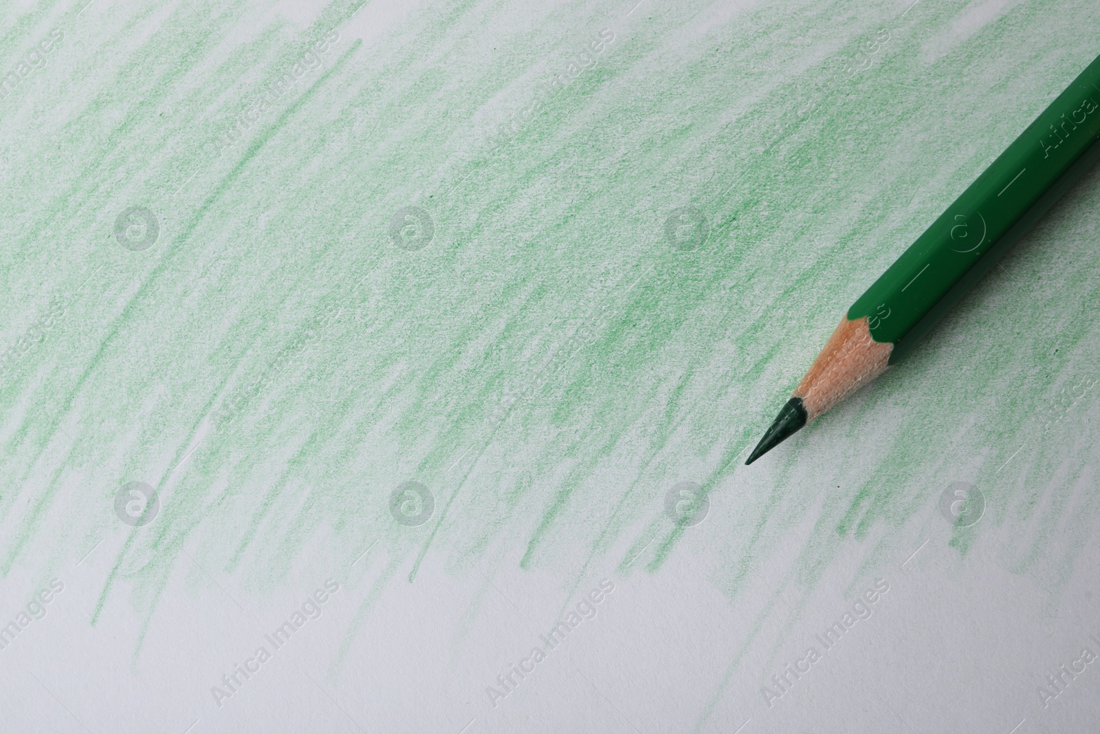 Photo of Green pencil on sheet of paper with drawing, top view