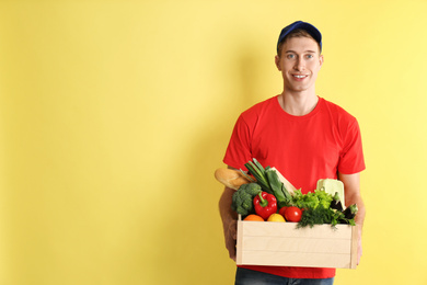 Photo of Courier with fresh products on yellow background, space for text. Food delivery service
