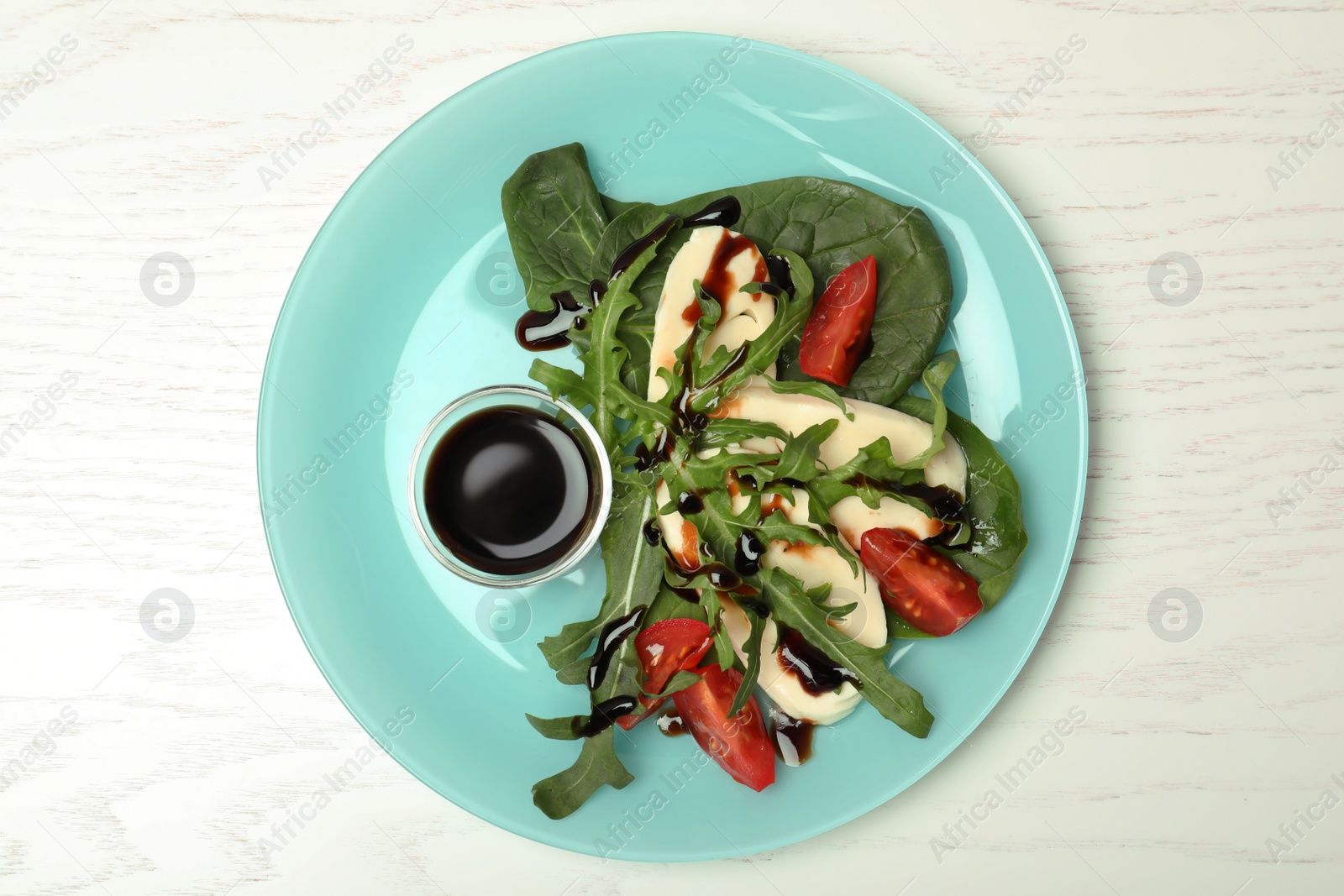 Photo of Plate with vegetable salad and balsamic vinegar on white wooden table, top view