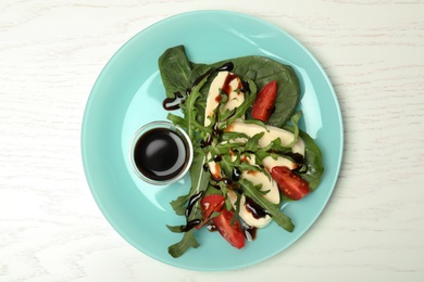 Photo of Plate with vegetable salad and balsamic vinegar on white wooden table, top view