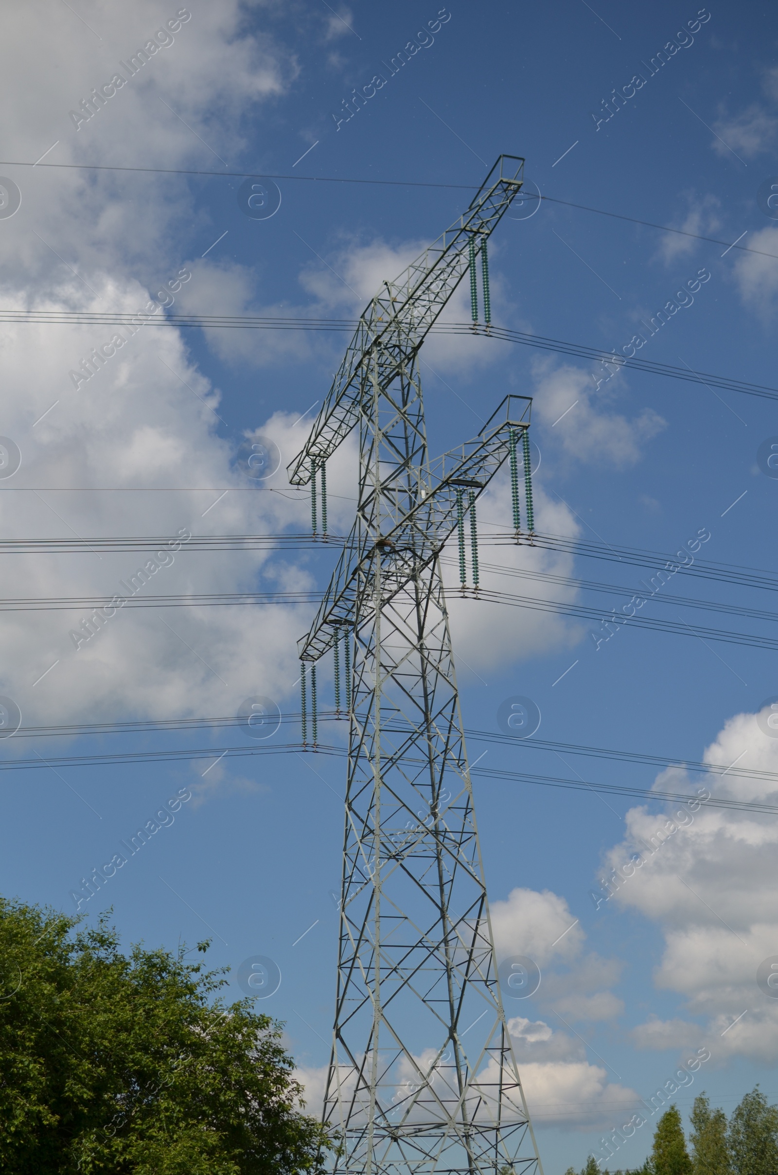 Photo of Modern high voltage tower against blue sky, low angle view