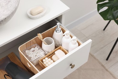 Different bath accessories and personal care products in drawer indoors, above view