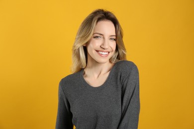 Photo of Portrait of happy young woman with beautiful blonde hair and charming smile on yellow background