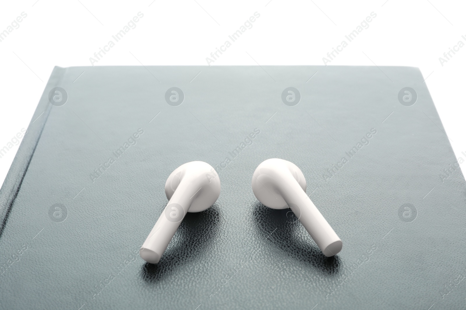 Photo of Bible and earphones on white background, closeup. Religious audiobook