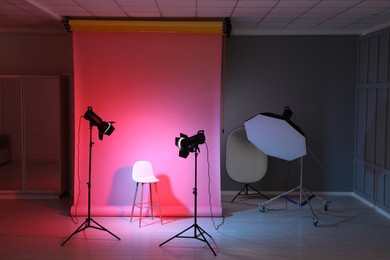 Photo of Photo background in neon lights and professional lighting equipment inside modern studio