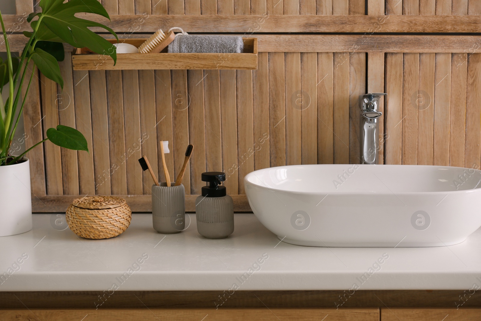 Photo of Toiletries and stylish vessel sink near wooden wall in modern bathroom